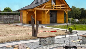 A wooden cabin with a pitched roof, a porch, and a stone wall. - Eco-friendly House by Goszcza Lake (Lubrza)