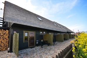 Guesthouse with a rustic charm, featuring a bench and a trash bin on a cobblestone path.