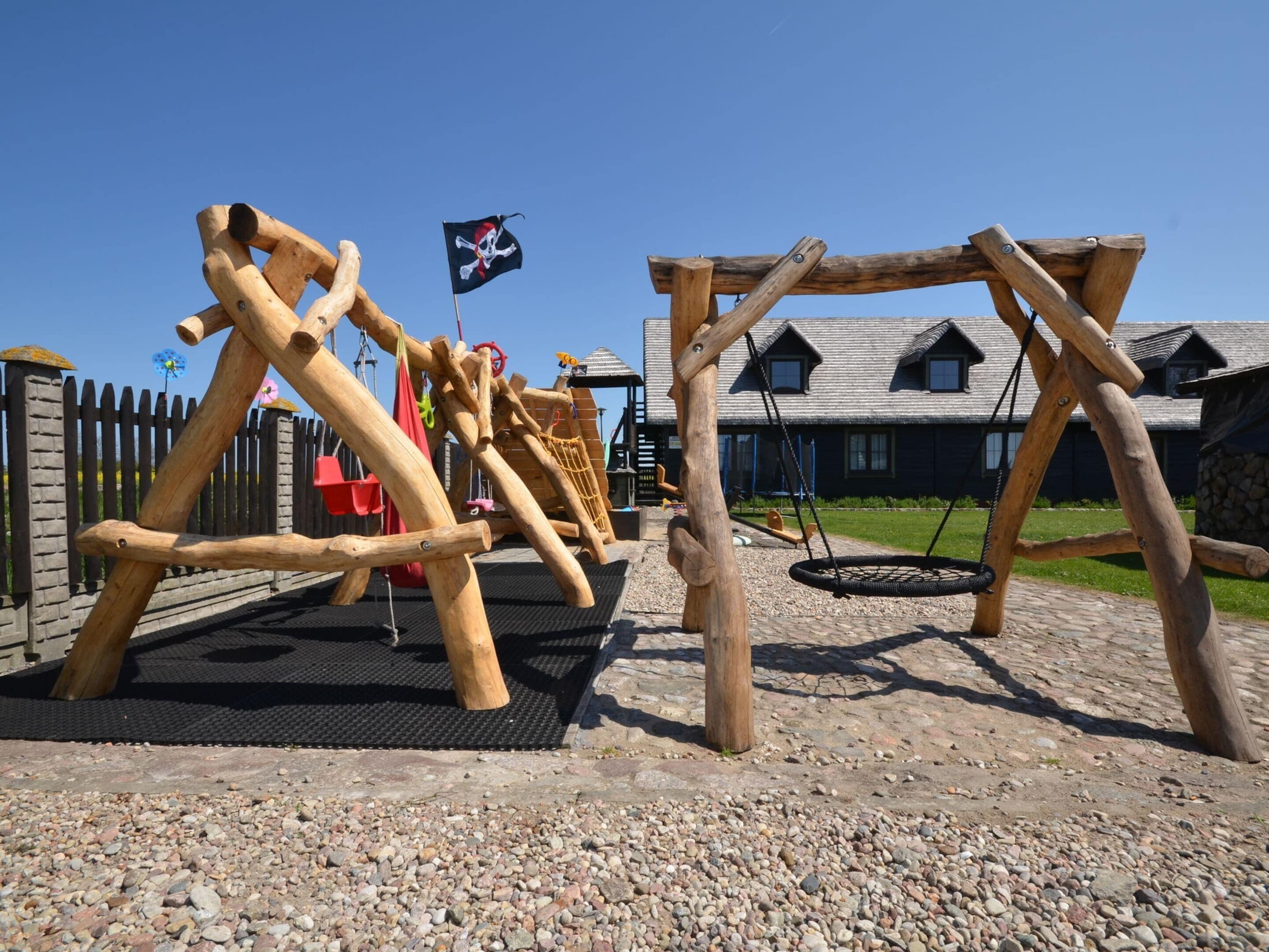 A playground with wooden climbing structures and a swing set.