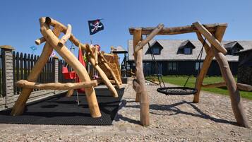 A playground with wooden climbing structures and a swing set.