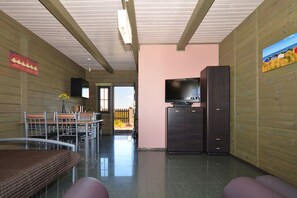 A room with a TV on a cabinet, a dining table with chairs, and a bench. - Cozy Studio 3 at the Seaside Agrotourism (Darlowo)
