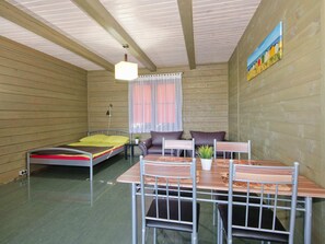 A room with two beds, a dining table with chairs, a small table with a plant, and a painting on the wall. - Cozy Studio 3 at the Seaside Agrotourism (Darlowo)