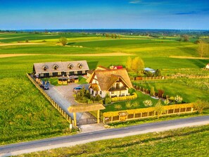 Escape to a serene countryside retreat with a main house and attached building amidst rolling hills and green fields.