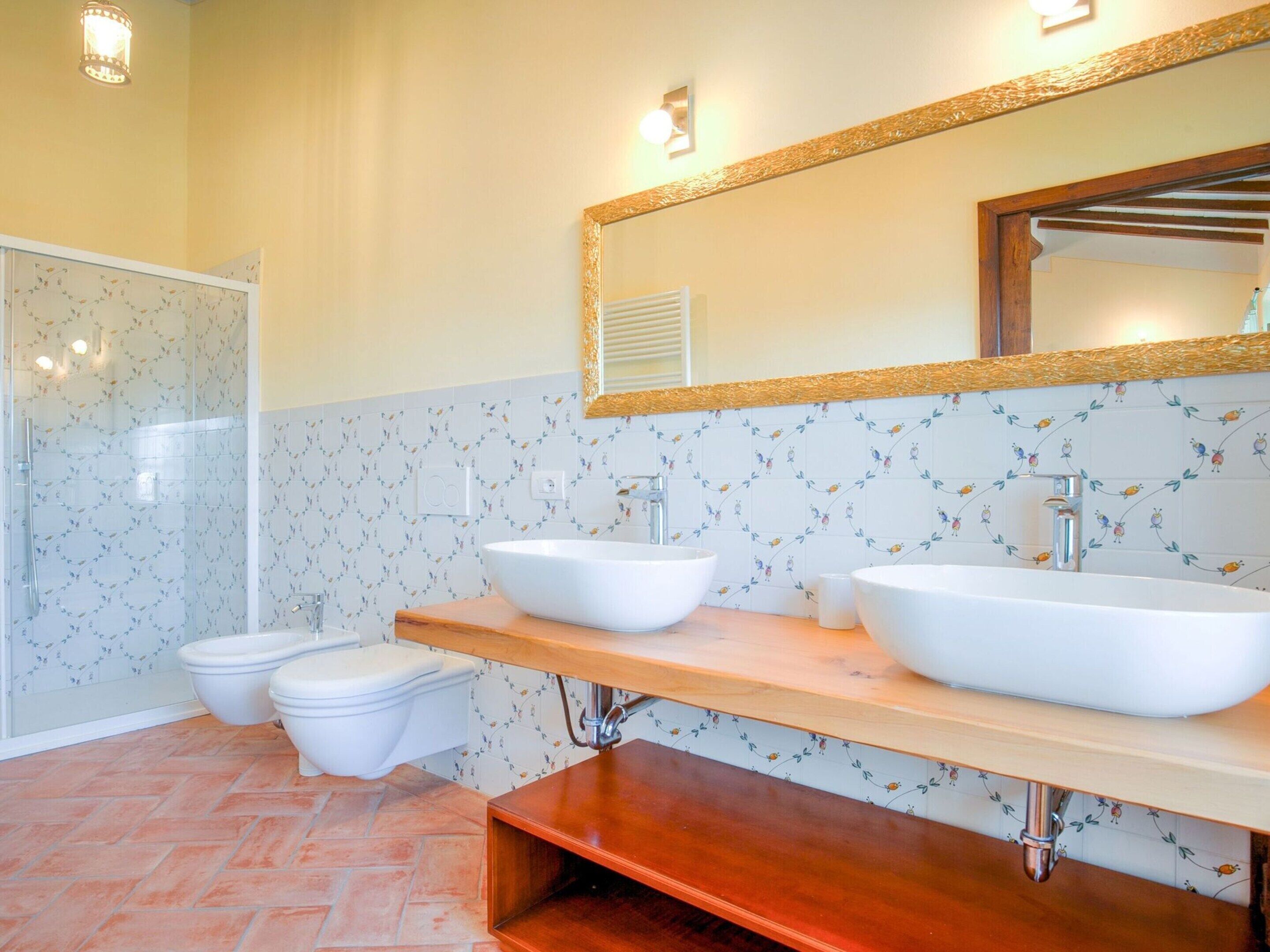 A bathroom with two sinks, a shower, and a toilet.