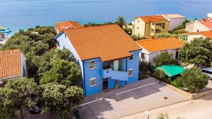 A coastal residential area with houses featuring orange-tiled roofs and a blue building with a balcony. - Seaside Apartment in Mandre (Kolan)