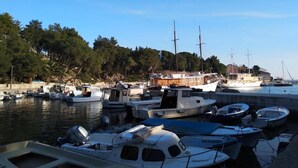 A marina with various boats docked, including sailboats and motorboats, surrounded by trees and buildings. - Seaside Apartment in Mandre (Kolan)