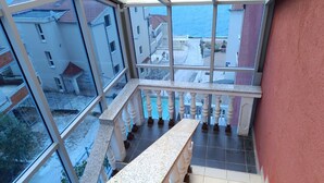 A high-rise building with a glass facade, a balcony with a stone balustrade, and a view of the sea and neighboring buildings. - Comforting Holiday Home in Okrug Gornji near Sea Beach (Okrug)