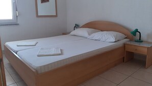 A neatly made bed with white linens and pillows, a wooden headboard, a nightstand with a lamp, and a painting on the wall. - Comfortable Holiday Home in Okrug Gornji (Okrug)