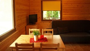L’intérieur d’un chalet accueillant, avec une table en bois, des chaises, un téléviseur et un canapé.
