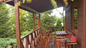 Une terrasse en bois avec une rambarde, une table et des chaises.