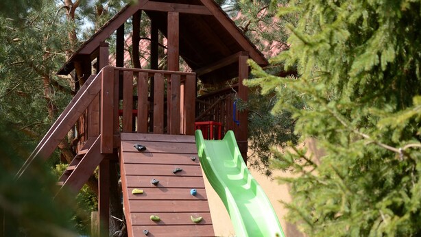 Une structure de jeu en bois, dotée d’un toboggan et de prises d’escalade.