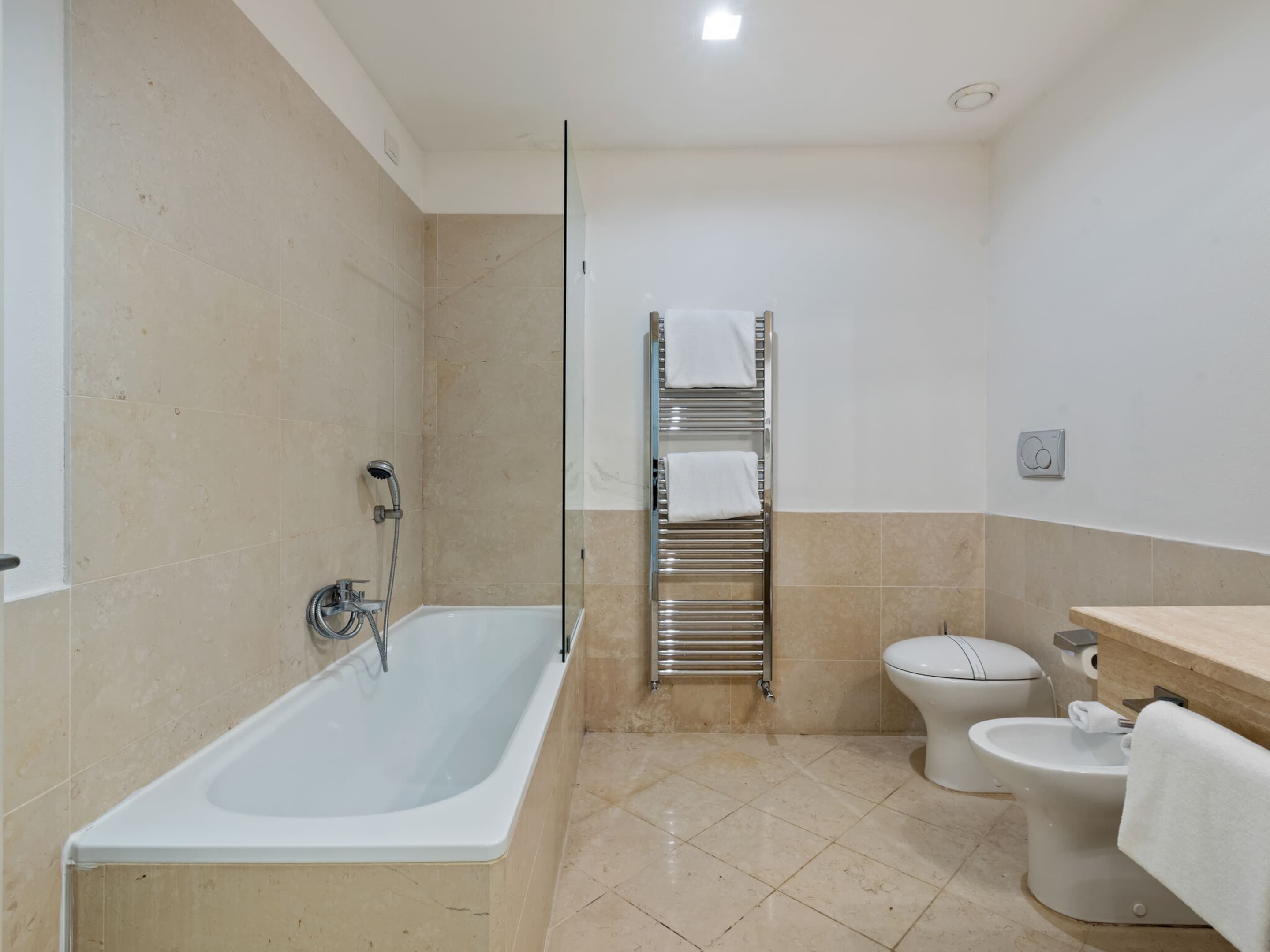 Un baño con bañera, inodoro y toallero.