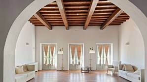 A spacious living room with a high ceiling, wooden beams, and large windows with curtains. - Garden & Wine Country Stay (Rignano sull'Arno)