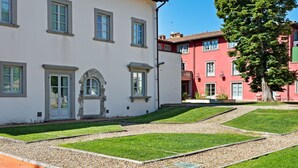 A courtyard with a white building, a red building, and a tree. - Garden & Wine Country Stay (Rignano sull'Arno)