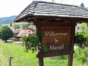 A wooden sign with the text "Willkommen In Marzell" surrounded by greenery and a rural landscape. - Apartment in Malsburg With Garden (Marzell)
