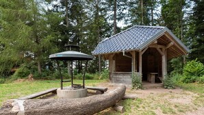 A rustic wooden structure with a tiled roof, surrounded by a natural forest setting.