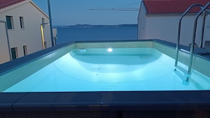 Ein Schwimmbad mit Blick auf das Meer und Gebäude im Hintergrund.