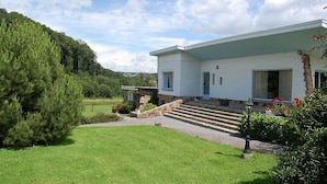 A modern house with a stone foundation, a front porch, and a well-maintained lawn. - Spacious Villa with Hot Tub & Sauna in Ardennes (Somme-Leuze)