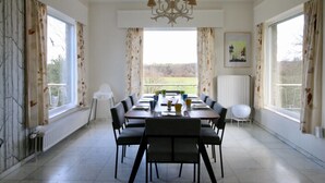 A dining room with a table set for six, chairs, a chandelier, and large windows with curtains. - Spacious Villa with Hot Tub & Sauna in Ardennes (Somme-Leuze)