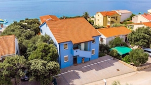 A coastal residential area with houses featuring orange-tiled roofs and a blue building with a balcony. - Seaside Bliss in Mandre (Kolan)