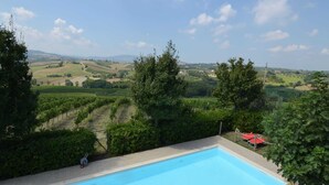A swimming pool with a view of vineyards and distant hills. - Apartment Amidst Vineyards & Blue Skies (Coriano)