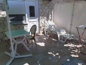 A patio area with a table and chairs, a covered seating area, and a stone wall.