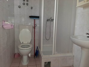 A bathroom with a toilet, a shower, and a sink.