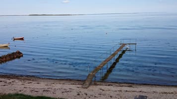 En rolig sø med en træbro, der strækker sig ud i vandet, omgivet af en sandstrand.