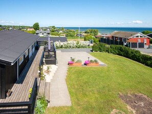 A residential area with a wooden deck, a paved patio, and a grassy lawn.