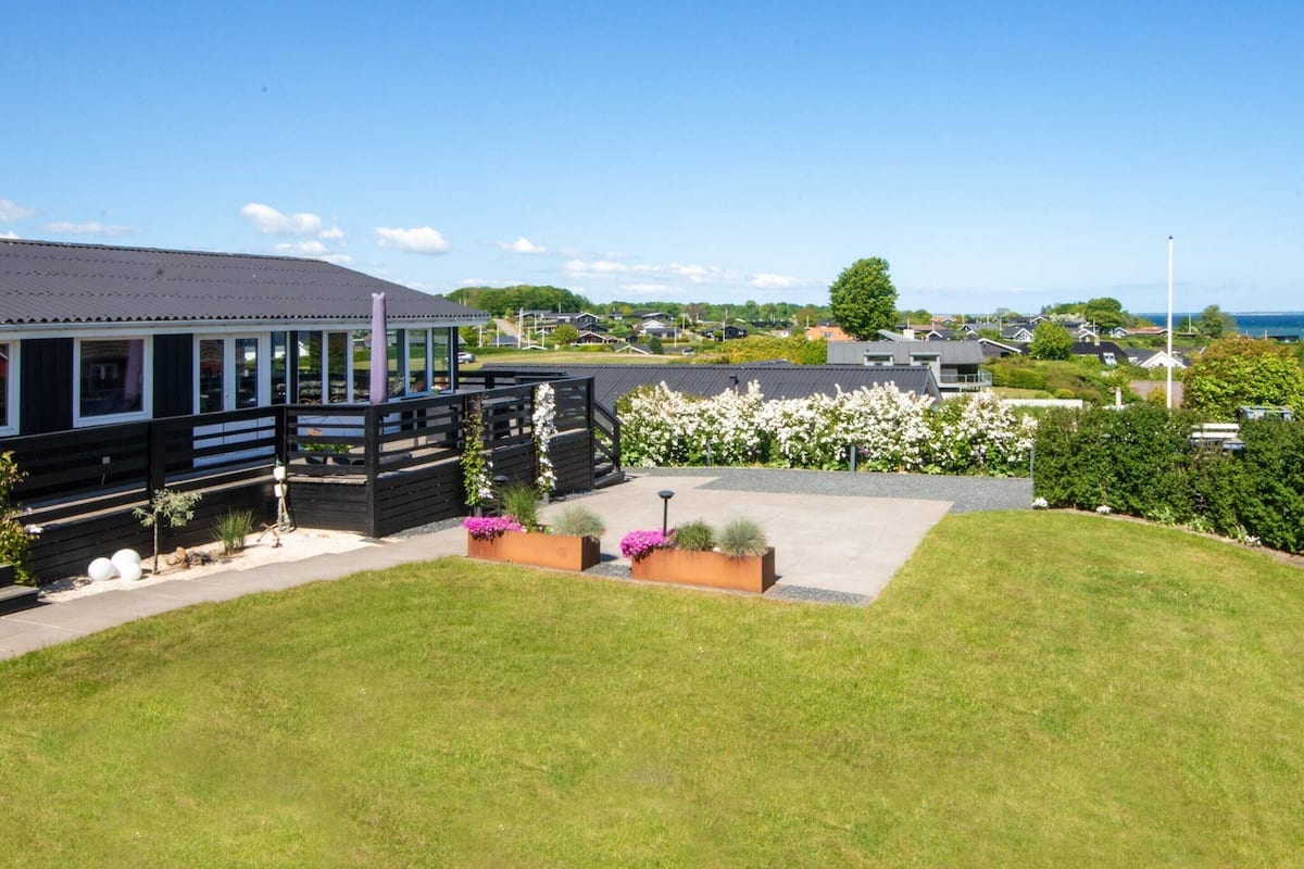 A modern building with a covered outdoor area, a grassy lawn, and a view of the sea.