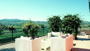A terrace with wicker furniture and potted plants, overlooking a scenic landscape. - Apartment in Coriano Near Vineyards & Beaches (Coriano)