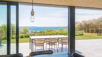 A dining area with a table and chairs, large windows, and a hanging light fixture.