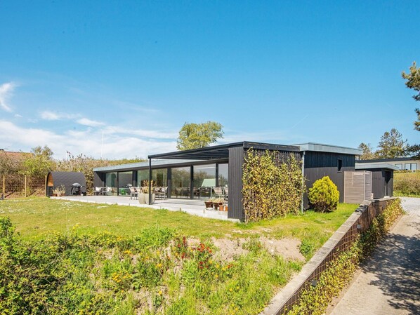 A modern house with a glass conservatory, outdoor seating, and a garden. - 5 Star Holiday Home in Ebeltoft (Ebeltoft)