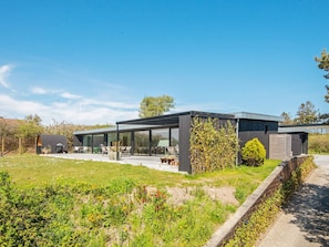 Une maison moderne dotée d’une extension en verre, d’un patio et d’un jardin.
