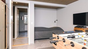 Ein modernes Zimmer mit einem Bett, einem Kicker und einem Fernseher.