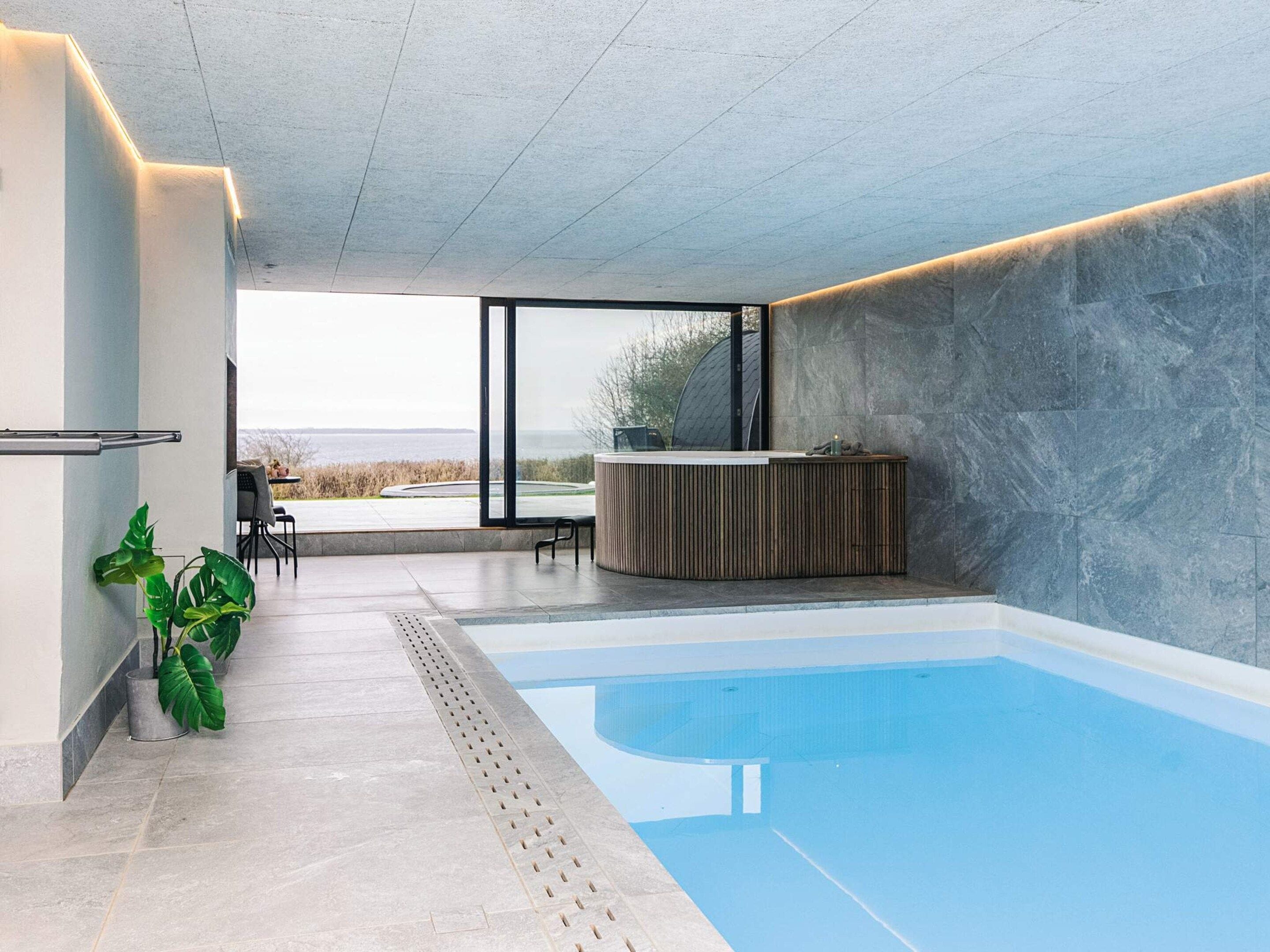 Una piscina interior moderna amb vista clara a l'exterior, una recepció i una zona de seients.