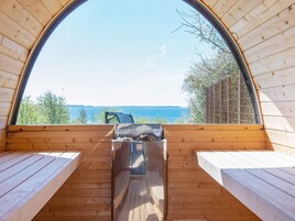 Una cabaña de madera con un amplio ventanal arqueado que da a un cuerpo de agua.