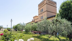 A building with a tower, surrounded by a garden with roses and trees. - Poolside Leisure in Empoli Hideaway (Empoli)