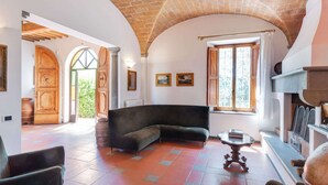 A spacious living room with a curved sofa, a fireplace, and a large window. - Poolside Leisure in Empoli Hideaway (Empoli)