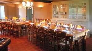 A dining room with a long table set for a meal, surrounded by wooden chairs.