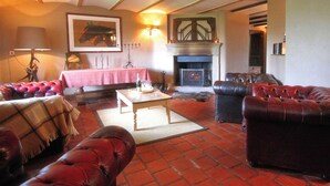 A cozy living room with leather sofas, a fireplace, and a table with candles.