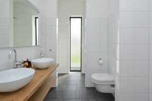 A modern bathroom with two sinks, a wooden vanity, a toilet, and a large mirror. - Luxury Villa on the Waterfront With Jetty (Zeewolde)
