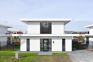 A modern two-story building with a flat roof, large windows, and a gated entrance.