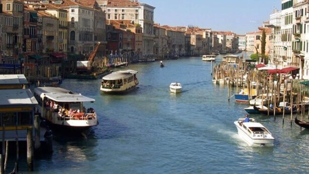 A canal with boats, buildings, and gondolas.