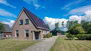 Une maison à deux étages avec un toit en pente, une allée en gravier et une pelouse verdoyante.