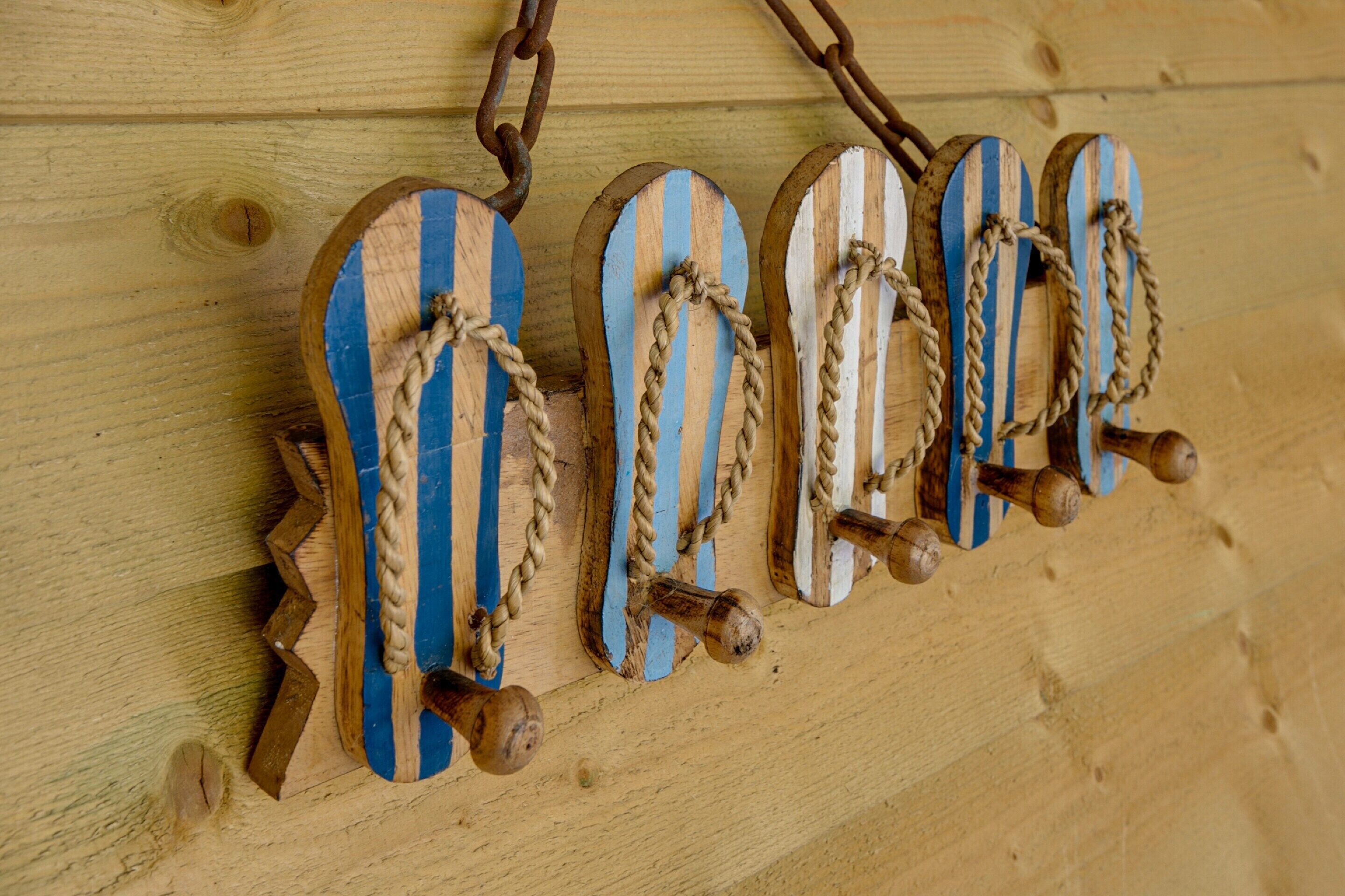 Eine Holzwand mit mehreren horizontal gestreiften Holzobjekten, möglicherweise Dekoration oder Möbel, die an einer Kette hängen.