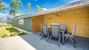 Un patio abrité avec une table et des chaises, un mur en bois et une vue sur le paysage.