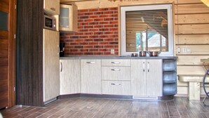 Cocina con armarios de madera, salpicadero de ladrillo y una ventana con persianas.