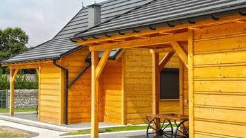 Relax on the covered porch with a bench and table, surrounded by a well-maintained property.