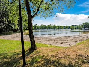 A park with a lake, trees, and a dirt path.